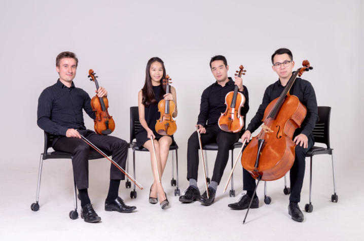 photo of Verdi Quartet seated in black chairs with string instruments with a white background