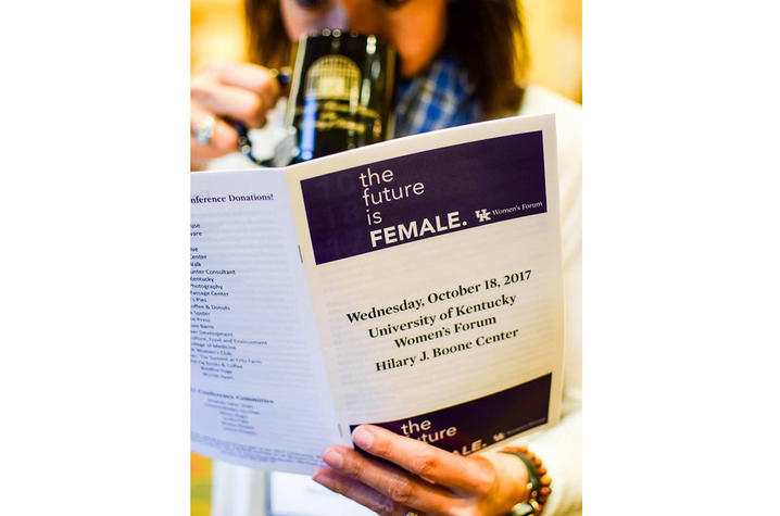 photo of woman looking at program from 2017 Women's Forum conference