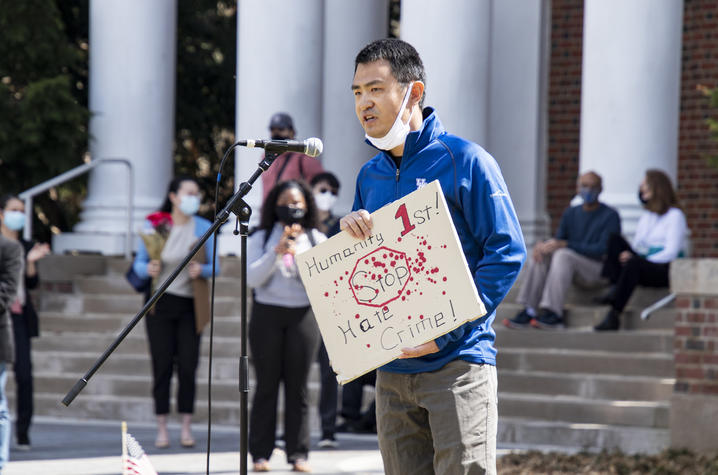 Yan Xia speaks at rally in front of Memorial Hall where others are sitting on the steps