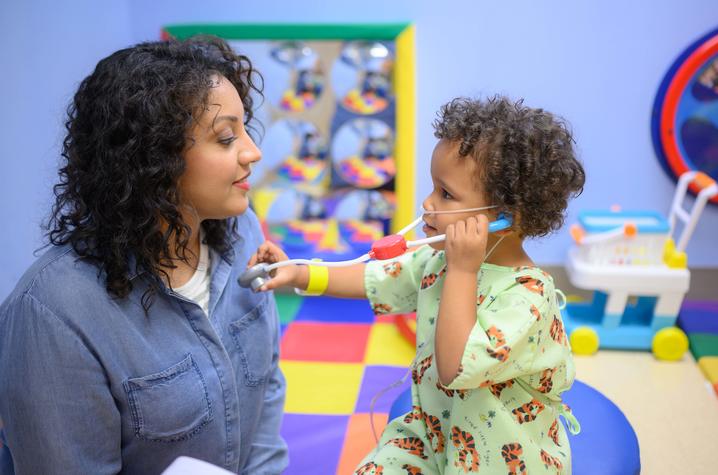 Image of small child pretending to listen to an adult’s heart with a toy stethoscope