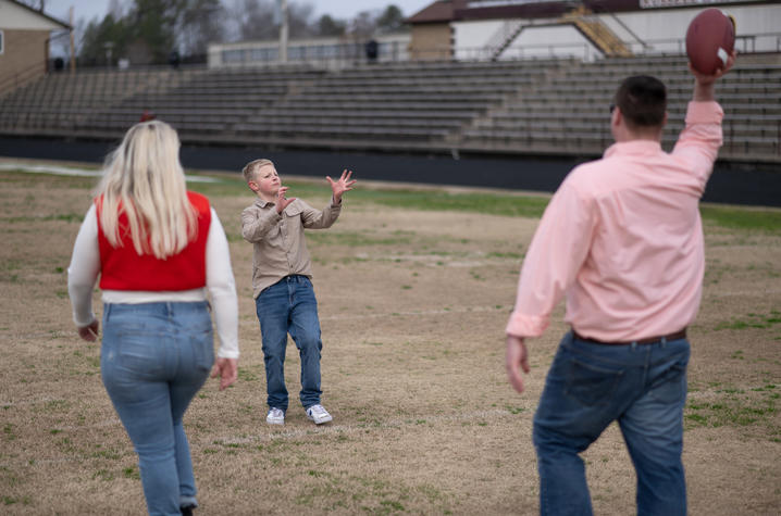 Image of William Dean throwing a football with his parents