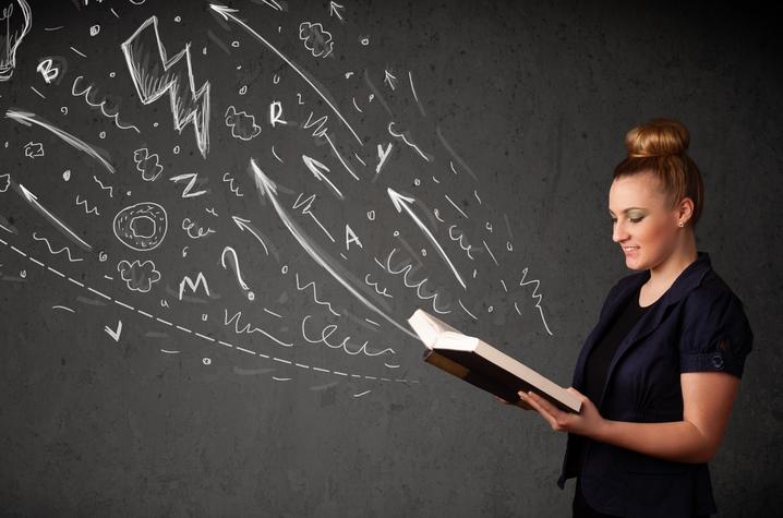 stock photo of young woman with book open and various letters, emblems flying out