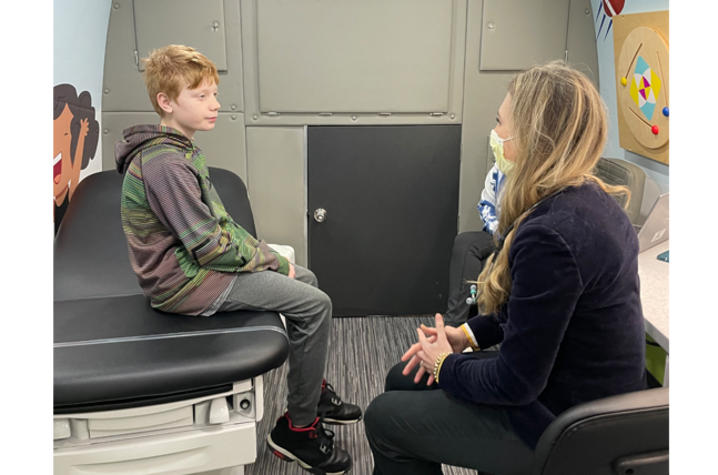 image of boy sitting in mobile clinic with Dr. Rsaza