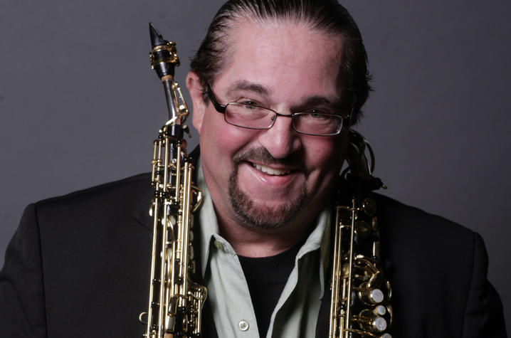 Headshot photo of Miles Osland with saxophones