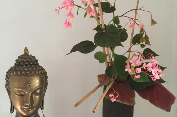 photo of Buddha bust and Asian-inspirec flower arrangement with bamboo