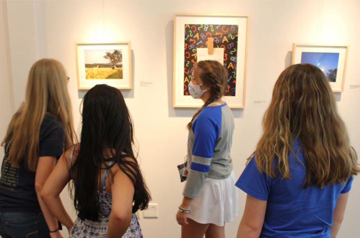 image of students looking at photographs at exhibit.