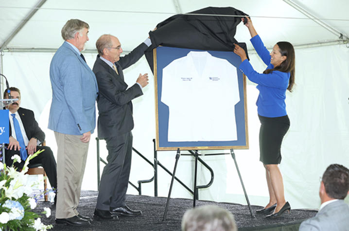 photo of Dr. Capilouto and Dr. Wendy Jackson unveiling medical coat for Dr. Michael D. Rankin