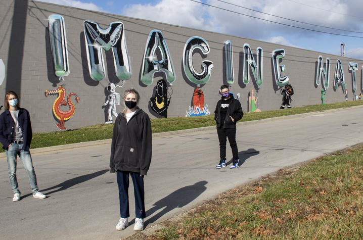 photo of 3 Guerilla Art students with "Imagine Nation" mural