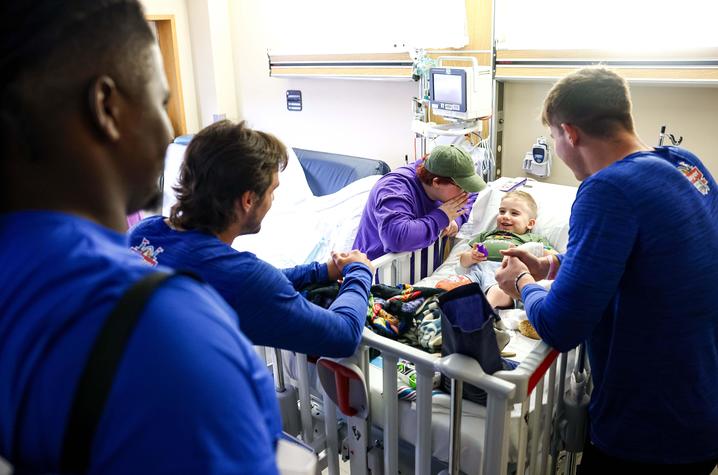 Image of football players with smiling patient in hospital bed