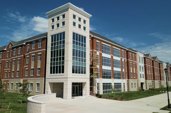 Exterior view of Kirwan-Blanding Hall, a multi-story University of Kentucky residence hall featuring red brick facades, large glass windows and a prominent central tower entrance.  Provide your feedback on BizChat