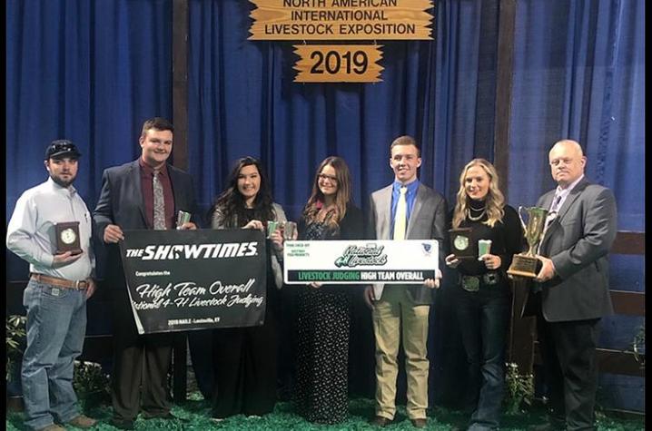 Winners pose with banners and awards against blue background