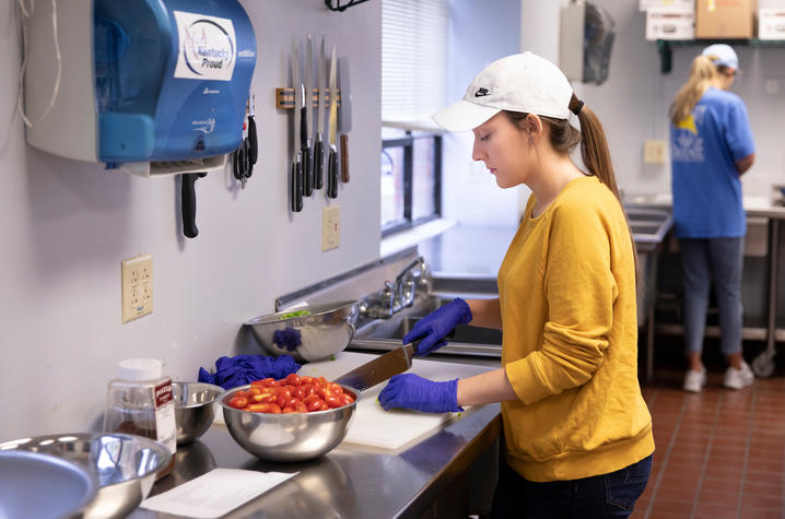 A student chops tomatoes in the kitchen of Erikson Hall.