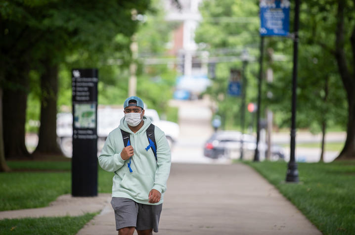 male student walking on campus wearing mask