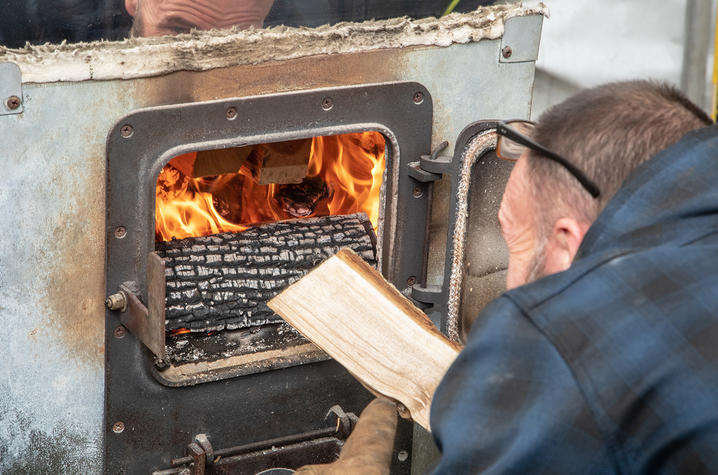 James Sword adding wood to the wood fire under the evaporator tank