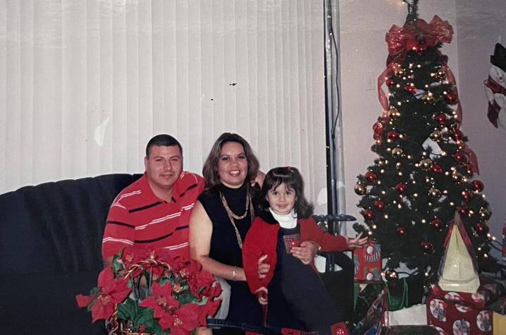 Young Monce Bravo and her parents at Christmas in front of the tree