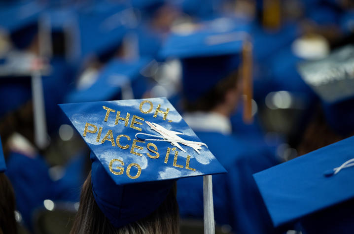 grad wearing mortarboard with writing on it that says "Oh, the places I'll go"