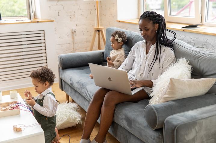 Women working on her laptop next to her daughter. 