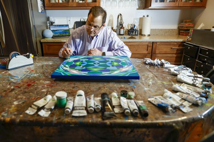 Dr. D'Orazio wakes up around 4 a.m. each morning to paint in his basement. He sets his supplies out on an old dining room table covered with a tarp and turns on his makeshift lighting system. Carter Skaggs | UK Photo