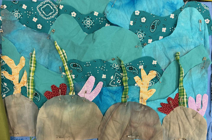 Kelsey Helton’s contribution to the Climate Quilt. A quilt panel showing underwater rocks with colorful coral against blue fabric.