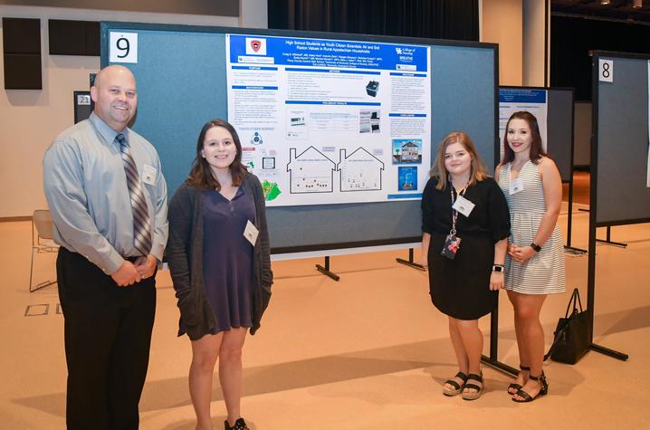 photo of teacher and students presenting research