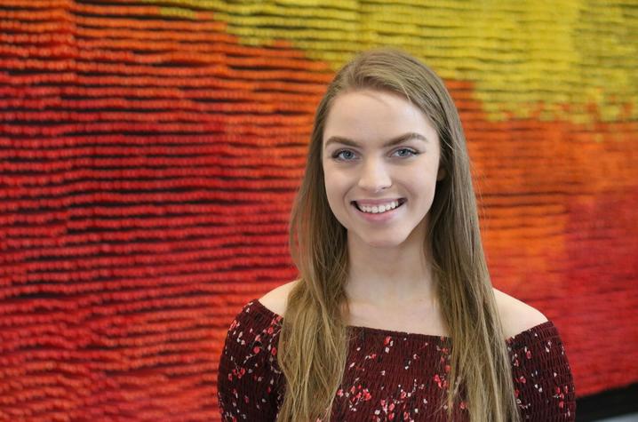 photo of Grace Bradley in front of pencil artwork in Gatton College