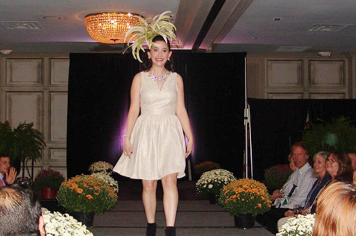 A girl in a gold dress walks down a runway.