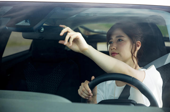 Woman adjusting her car mirror.