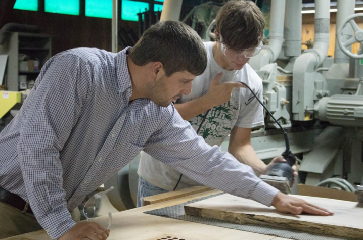 Chad Niman inspects Garrett Dunn’s work in a workshop.