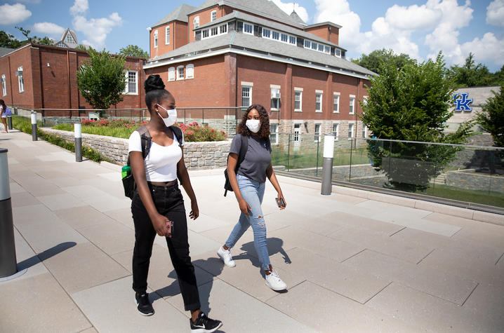 Photo of two female students in COVID-19 protective masks walking on campus