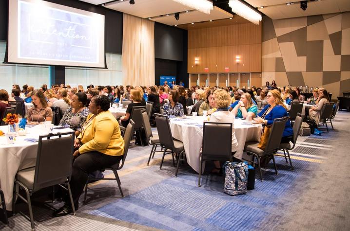 Women attending the UKWM conference seated at tables wearing various colors of clothing