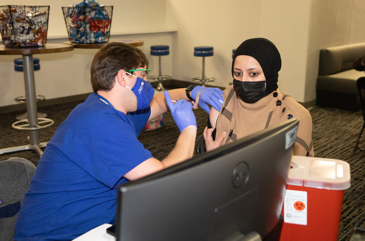 woman receives covid shot in her right arm at UK vaccination clinic