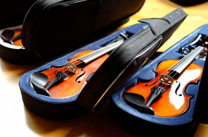 photo of 3 violin cases with violins on floor