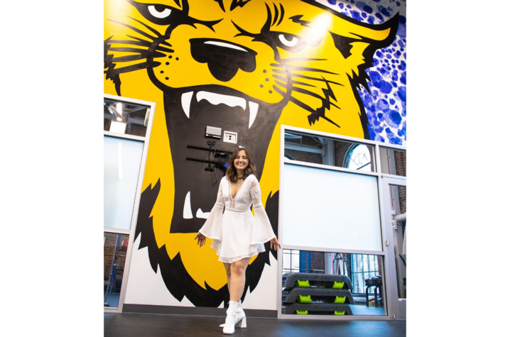 photo of Selma Odobasic in white dress in front of wildcat mural
