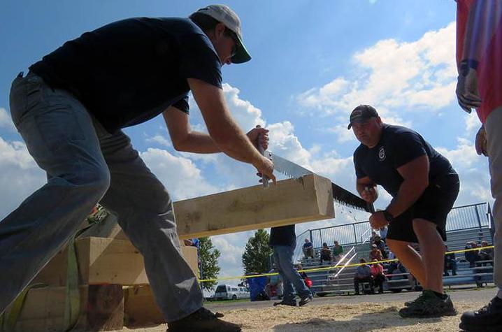 Men participating in wood sawing competition on each ends of wooden log