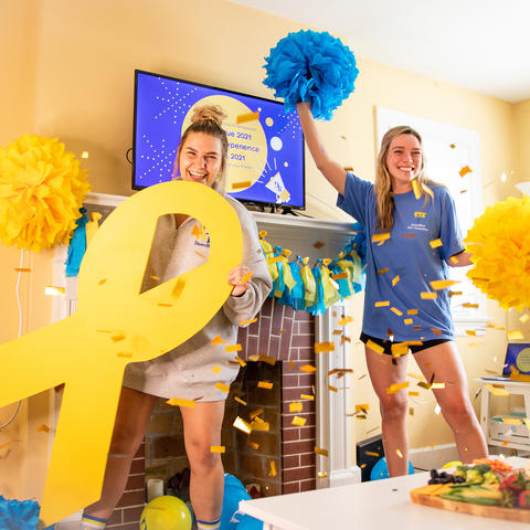 Two females with DanceBlue yellow ribbon, confetti and pompoms 