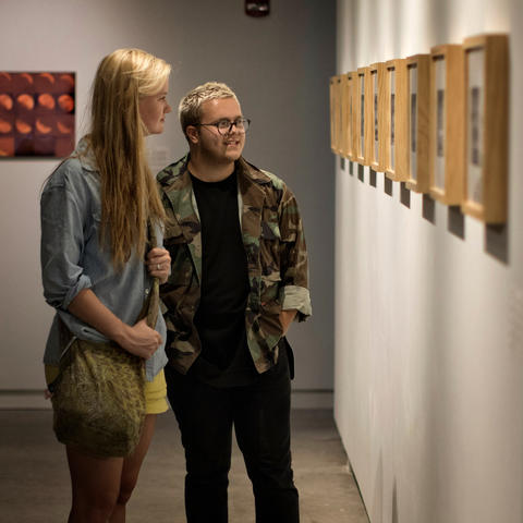 photo of 2 students looking at David Wischer's work - “Faculty Series: Vol. I” 