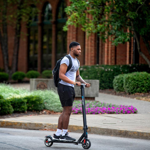 Photo of student riding scooter throughout campus