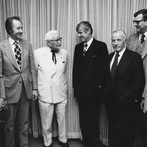 Colonel Harland Sanders in white suit, Governor John Y. Brown, Jr., John Y. Brown, Sr., UK Vice President Ray Hornback, and Chancellor of Medical Center Peter Bosomworth at the Sanders-Brown building dedication.