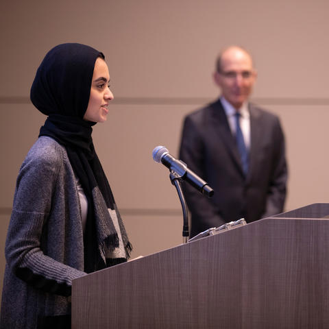 photo of Hadeel Abdallah speaking at BOT meeting with President Capilouto in background
