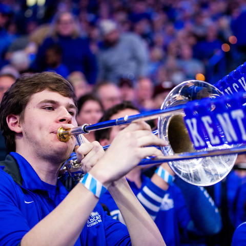 photo of John Schulz with blue tiles spelling out Kentucky on trombone slide