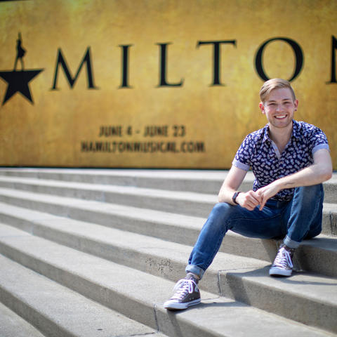 photo of Patrick Garr seated outside The Kentucky Center sign for Hamilton