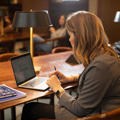 A student sitting, working on a laptop. 