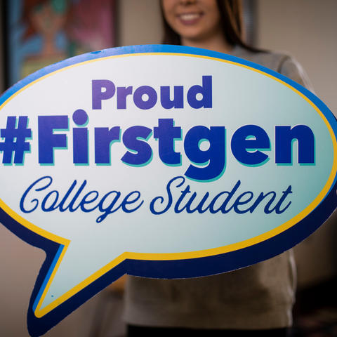 Student holding a "proud #firstgen college student" poster. 
