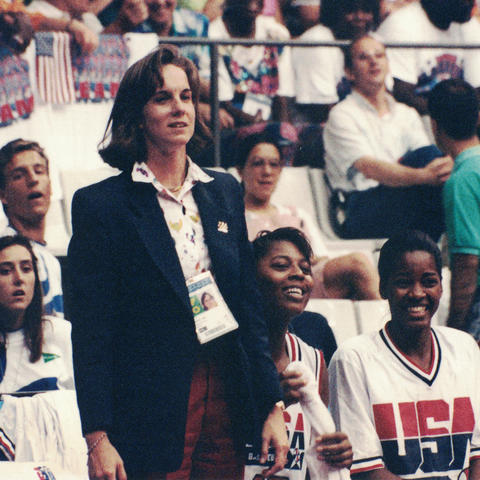 Dr. Ireland stands to the left of the screen with 3 members of the US women's basketball team sitting to her right