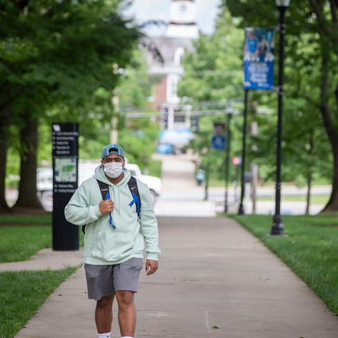 photo of student walking on campus wearing mask