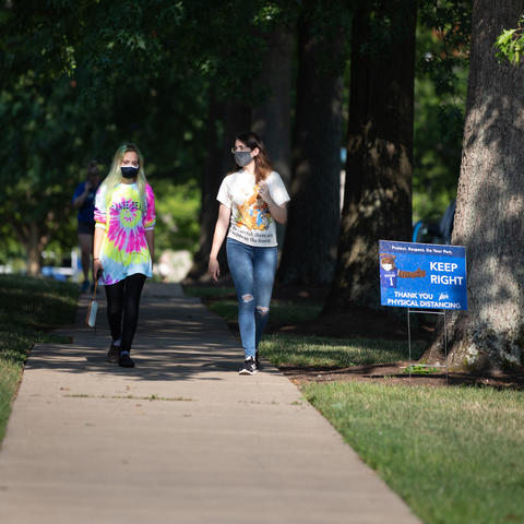 Image of two students walking on campus wearing face masks