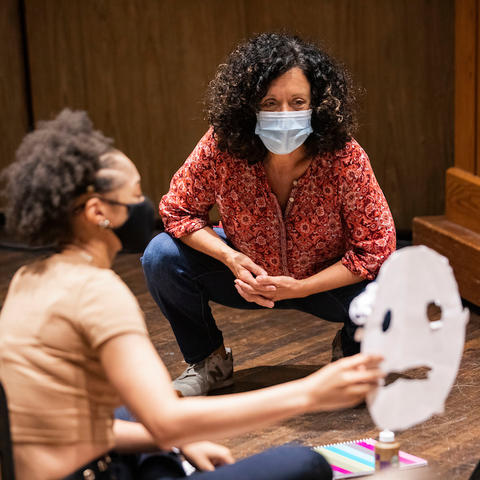 photo of Nancy Jones looking at students Greek mask in theatre class