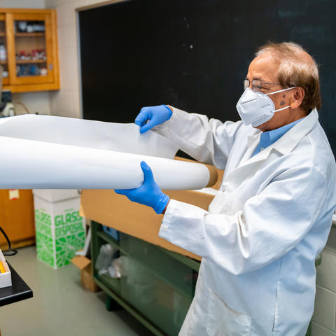 Dibakar Bhattacharyya in the lab with a large sheet of membrane material. Ben Corwin | Research Communications