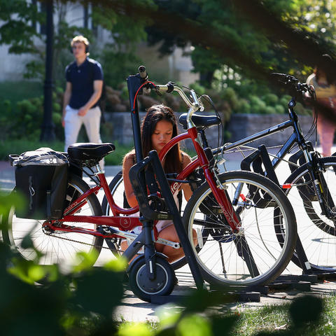 a student is securing her bike to the bike rack using a lock. 