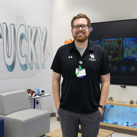 Image of Cody Dean standing in front of video game screen